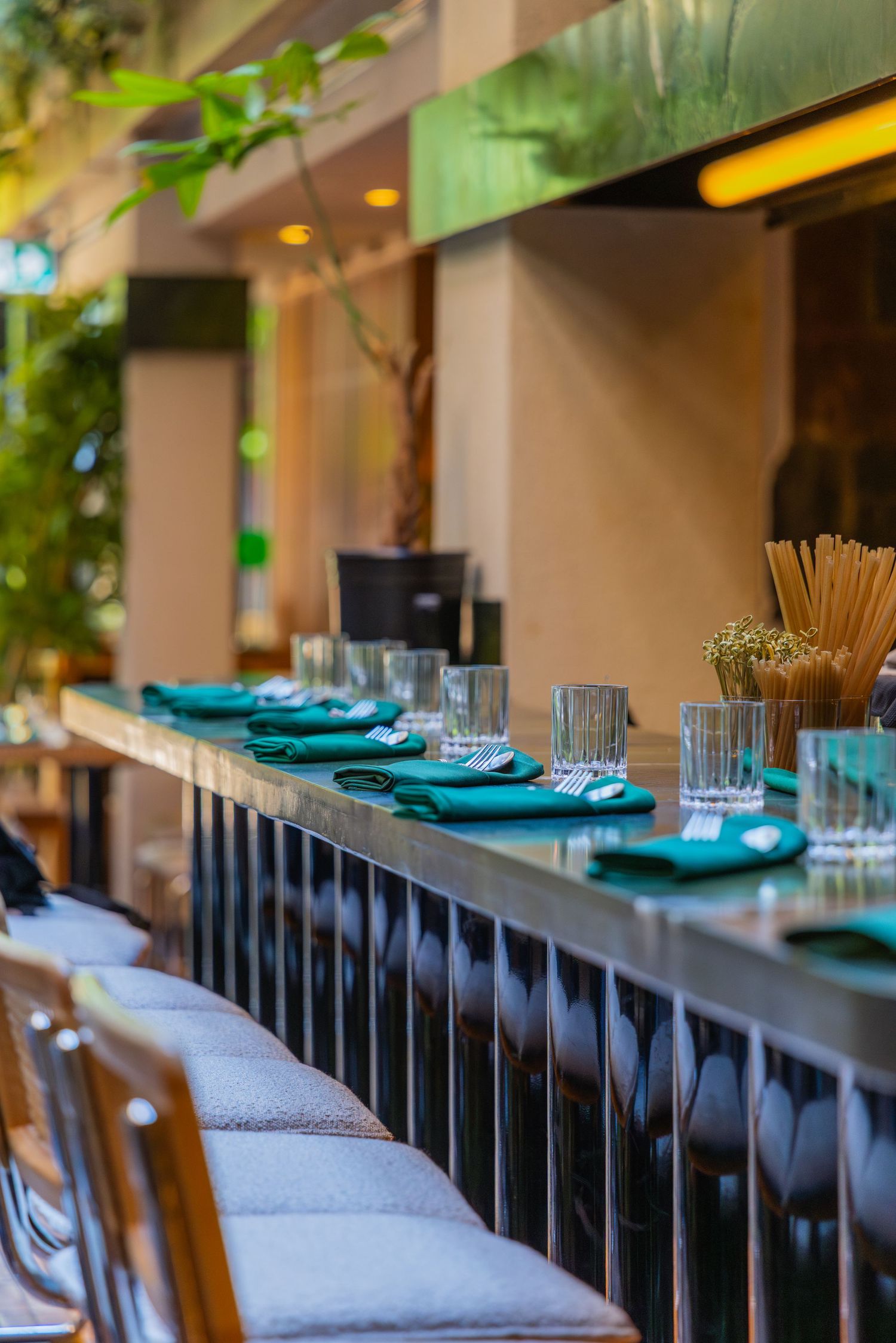 Contemporary restaurant seating with turquoise plates and elegant table settings along a cushioned bench under ambient lighting.