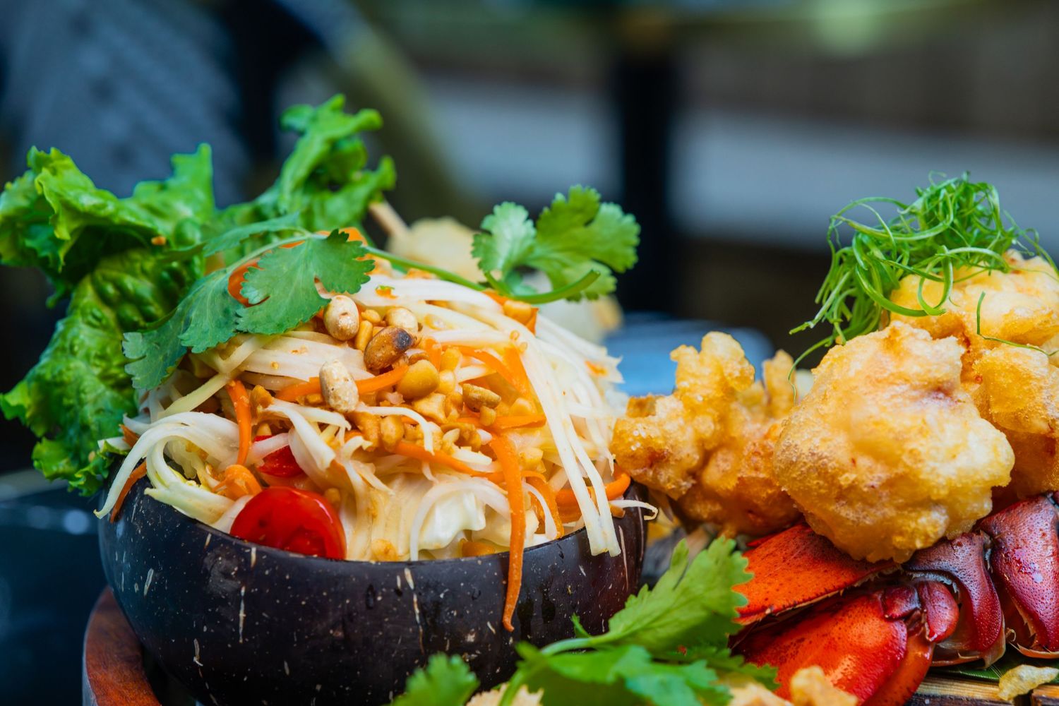 Fresh seafood bowl featuring crispy shrimp, mixed vegetables, and colorful garnishes served in a dark ceramic dish.
