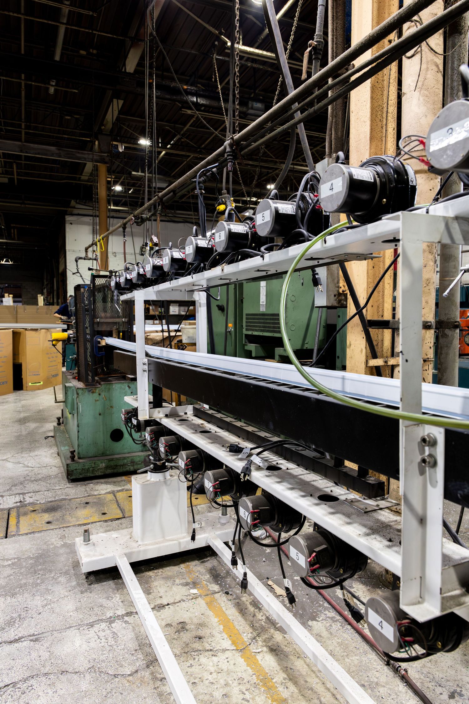 Industrial manufacturing equipment showing rows of mounted motors and machinery controls on metal racks in a warehouse setting.
