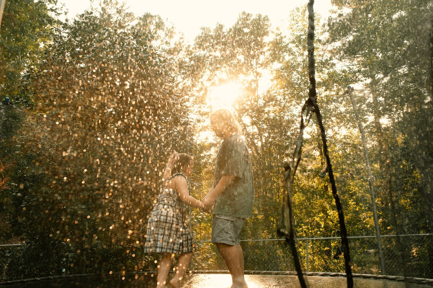 Son and daughter playing in water hose rain on trampoline in family photos in Cartersville, GA.