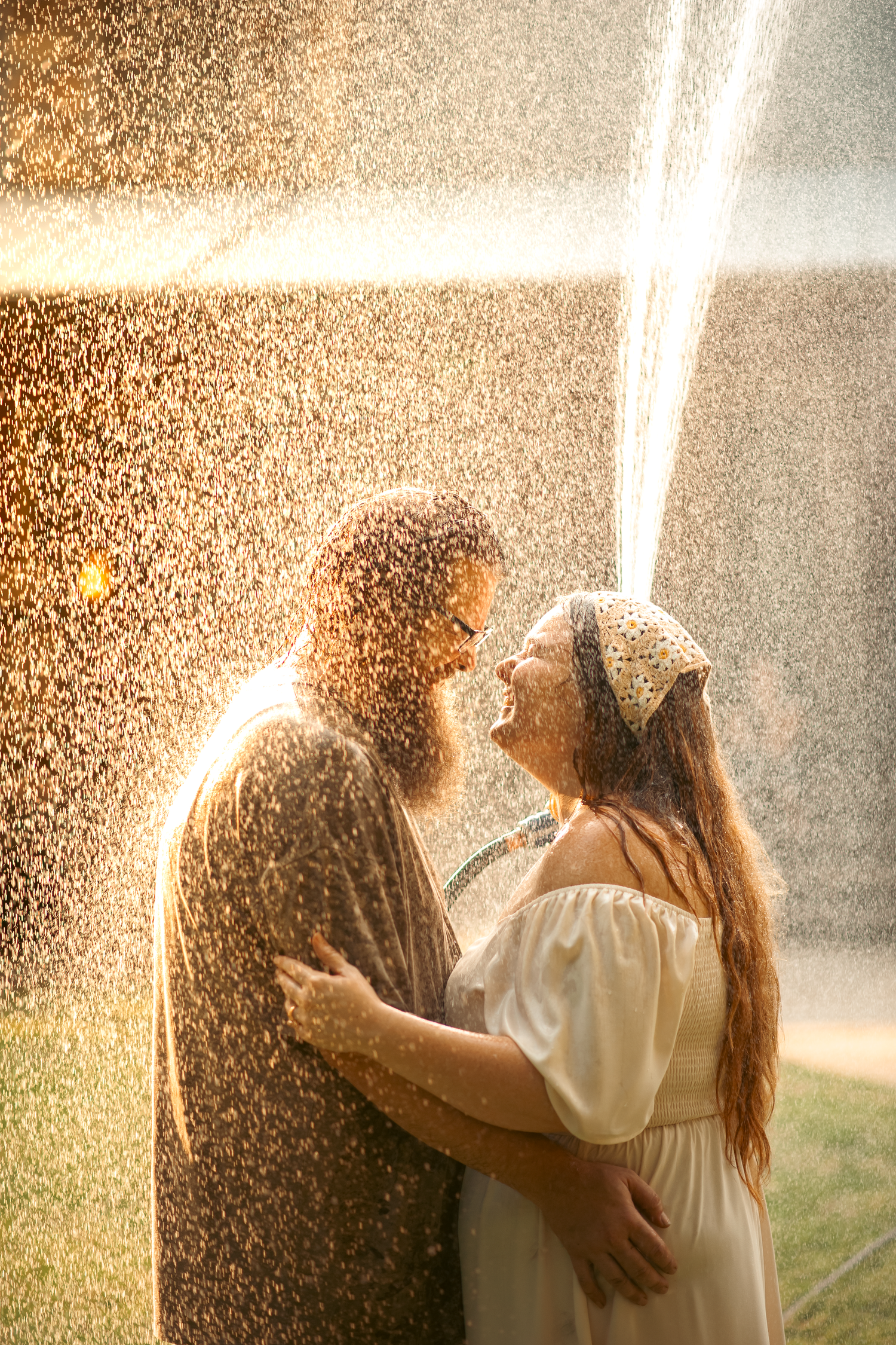 Husband and wife holding each other smiling under water hose in family photos in Cartersville, GA.