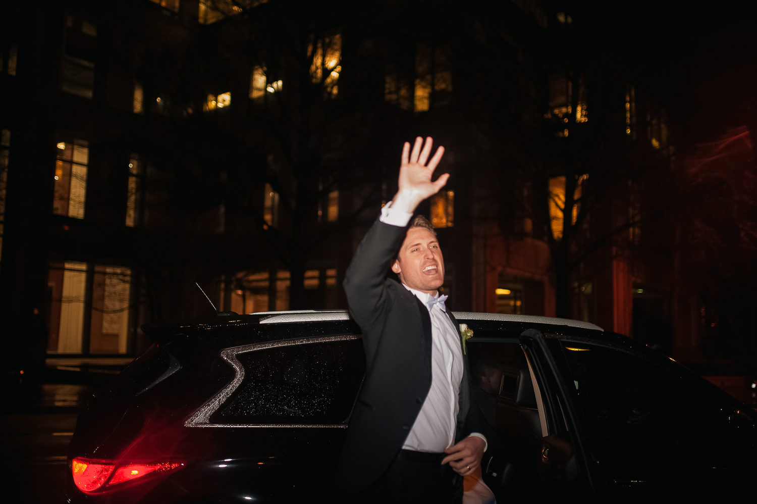 Groom waving during the sendoff as they get into a car and leave after their January wedding at Wimbish House in Atlanta, GA.