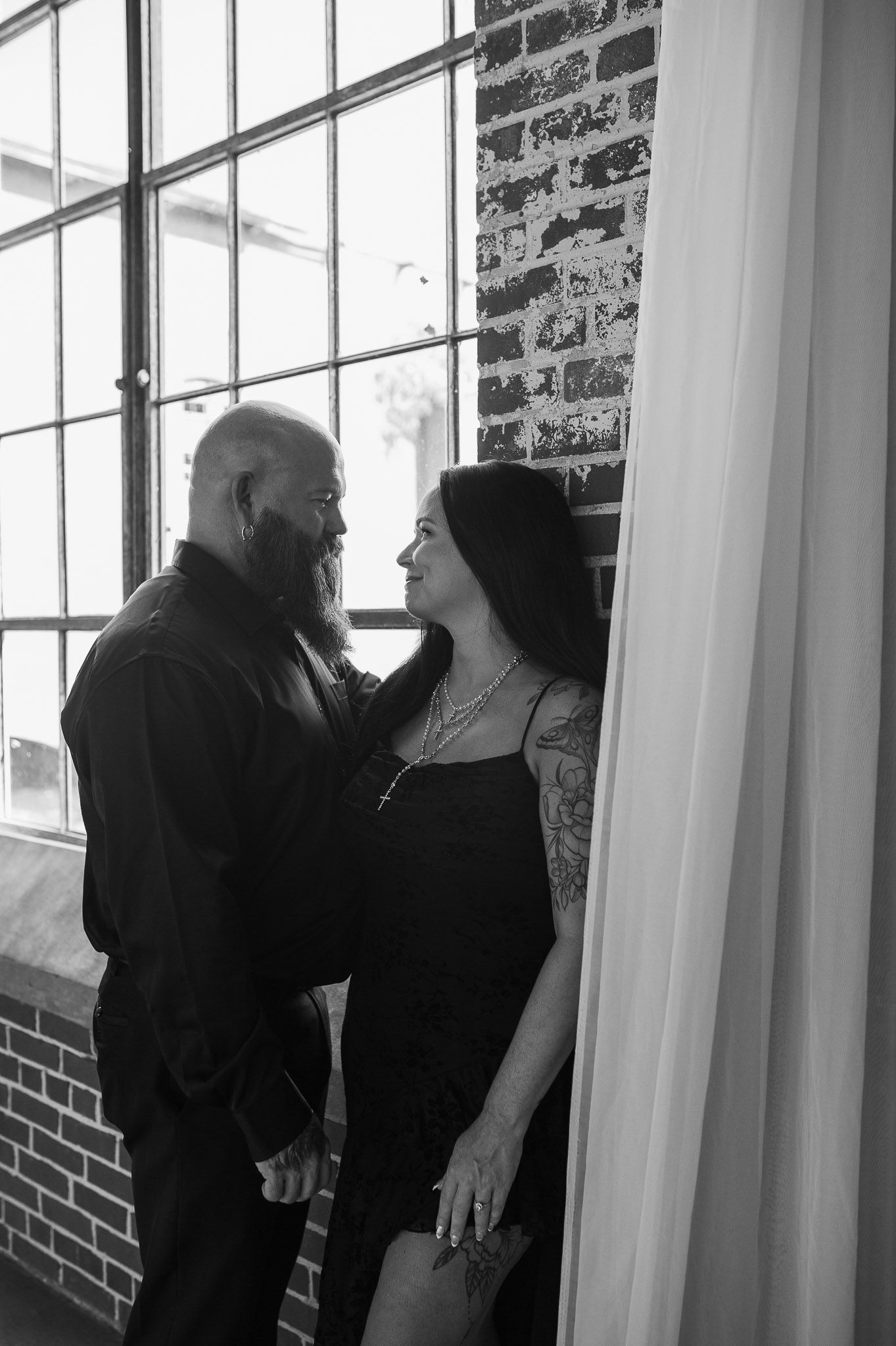 Black and white shot of couple at engagement session in dye room in Lindale Mill.