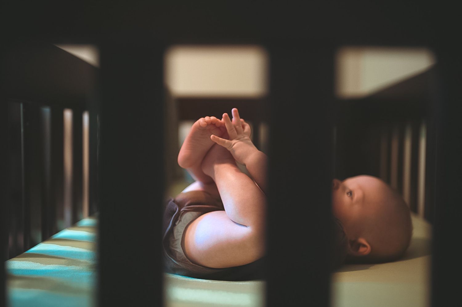 Baby playing with feet in crib during newborn session in Dallas, GA.