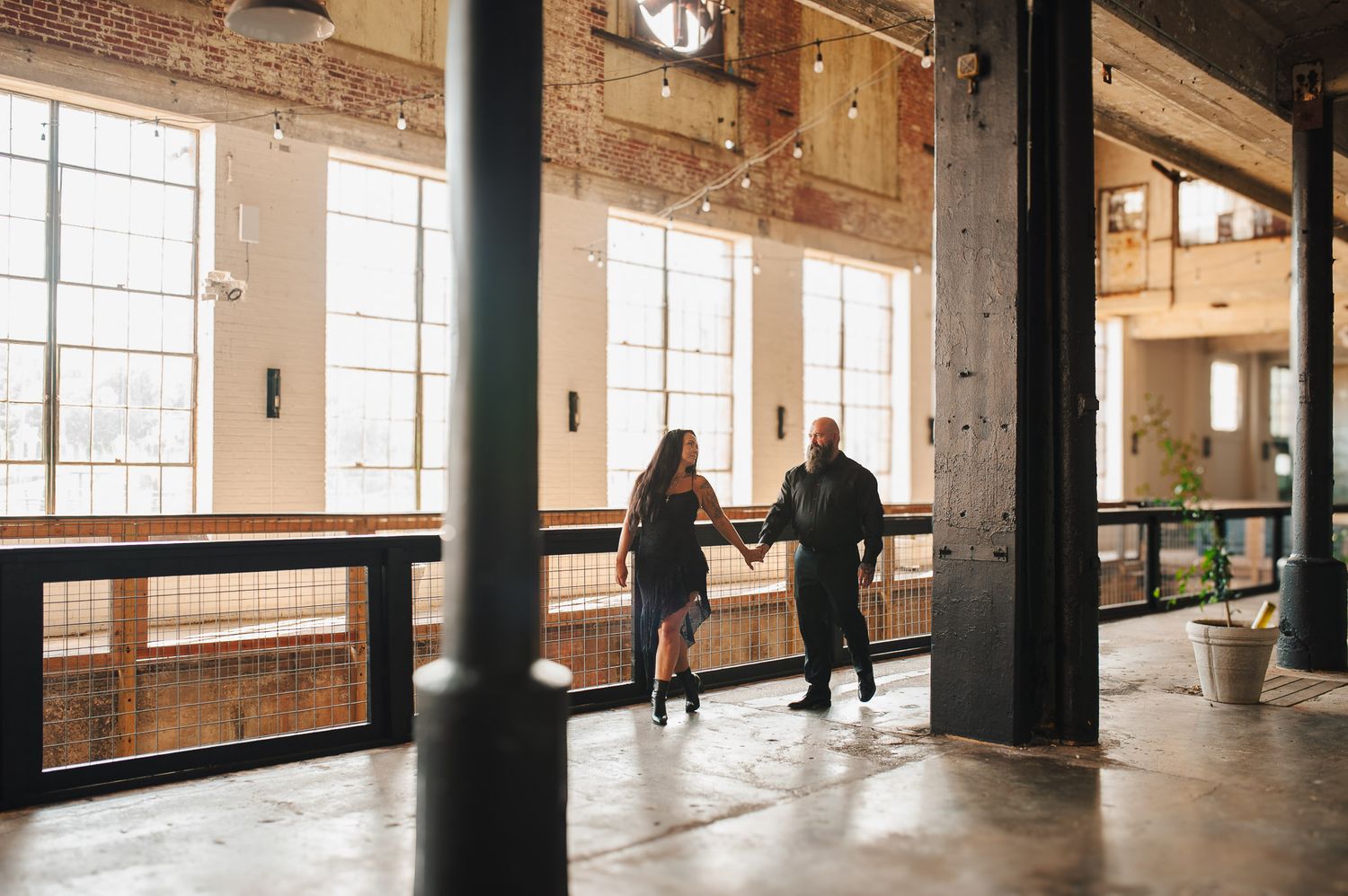 Couple holding hands walking through industrial Lindale Mill in Rome, GA for cinematic shot.