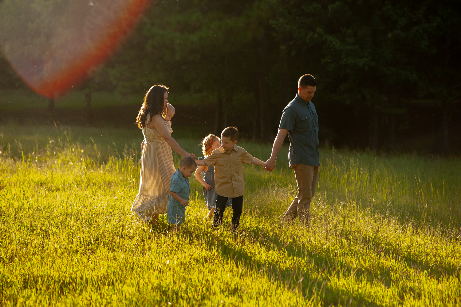 Family of six walking in a field with golden glow in portrait session in Cartersville, GA.