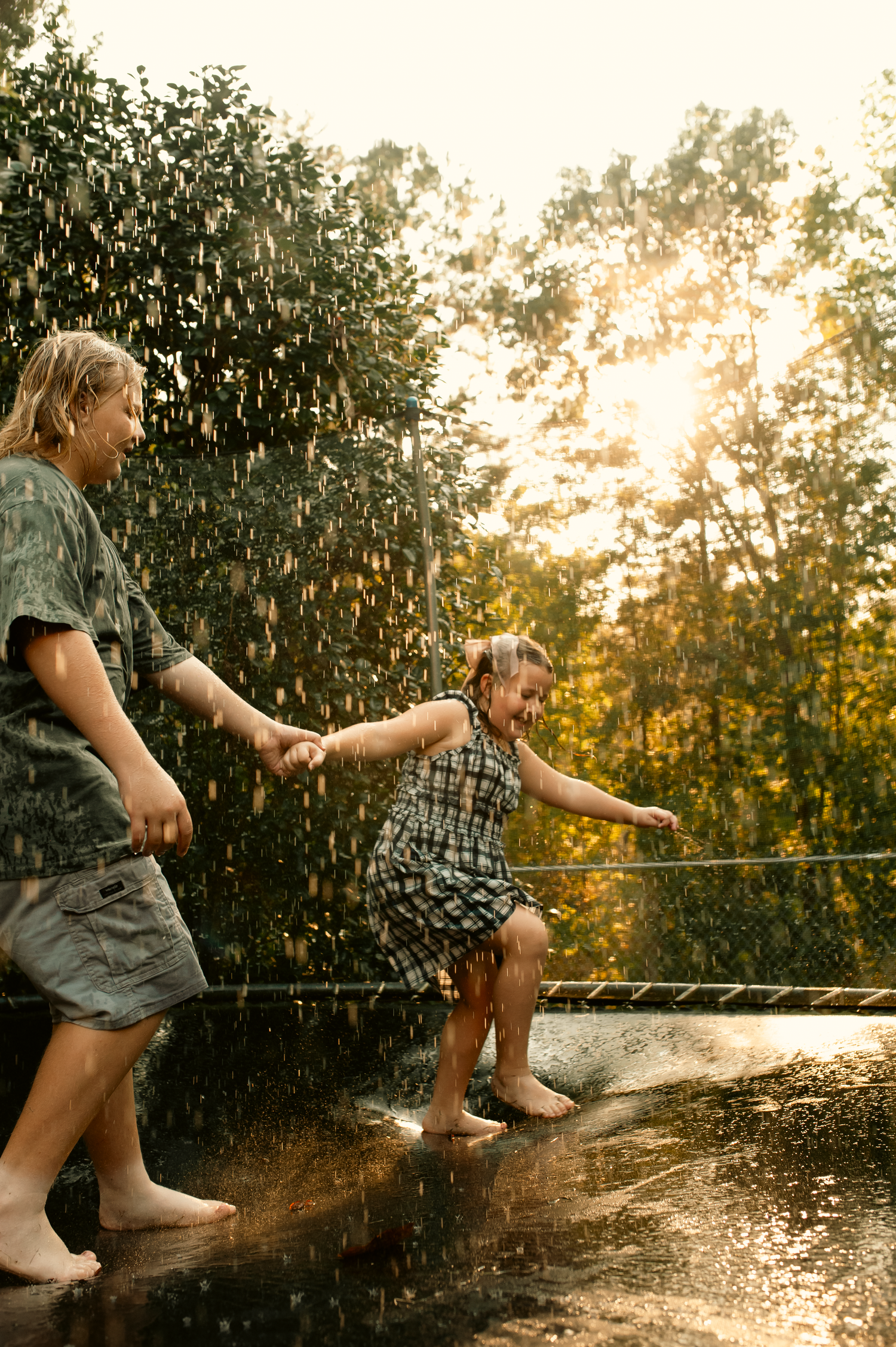 Teenage son and 7 year old daughter playing with water hose on trampoline for family photos in Cartersville, GA.