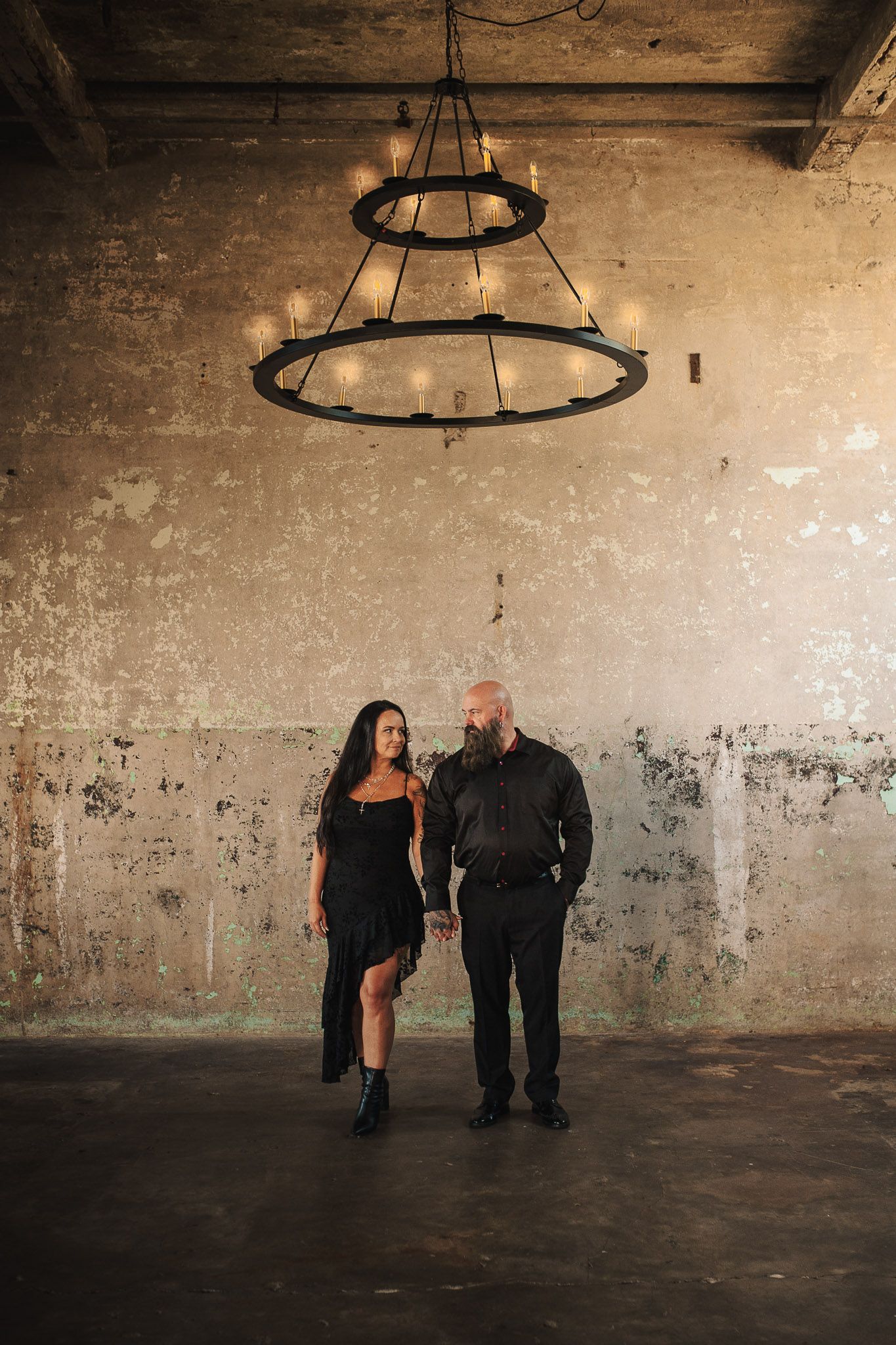 Couple posing under chandelier in Lindale Mill for engagement photo shoot.