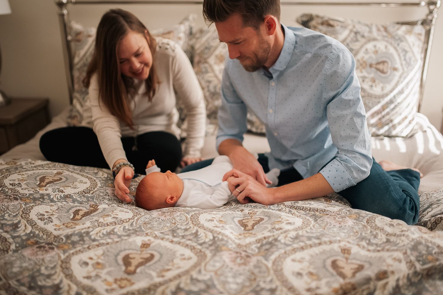 Mom and dad playing with baby on bed in at home newborn session outside of Atlanta, GA.