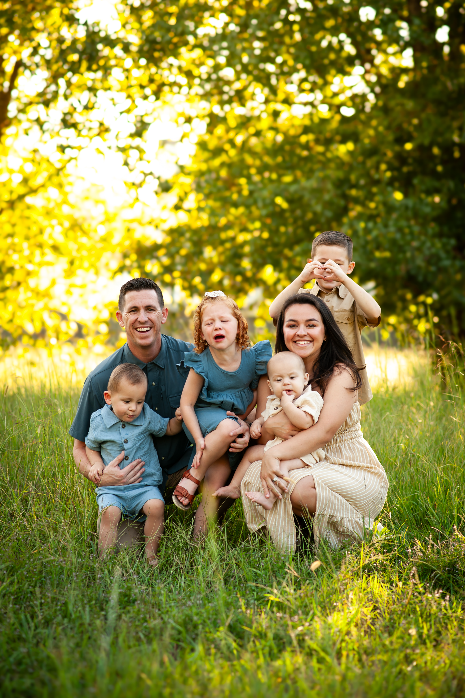 Fall family portrait with crying child in field and golden glow in Cartersville, GA.