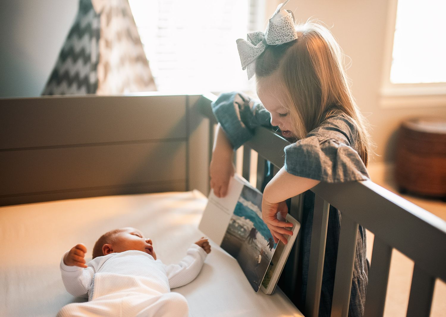 Big sister reading baby a book in at home lifestyle newborn session in Atlanta.