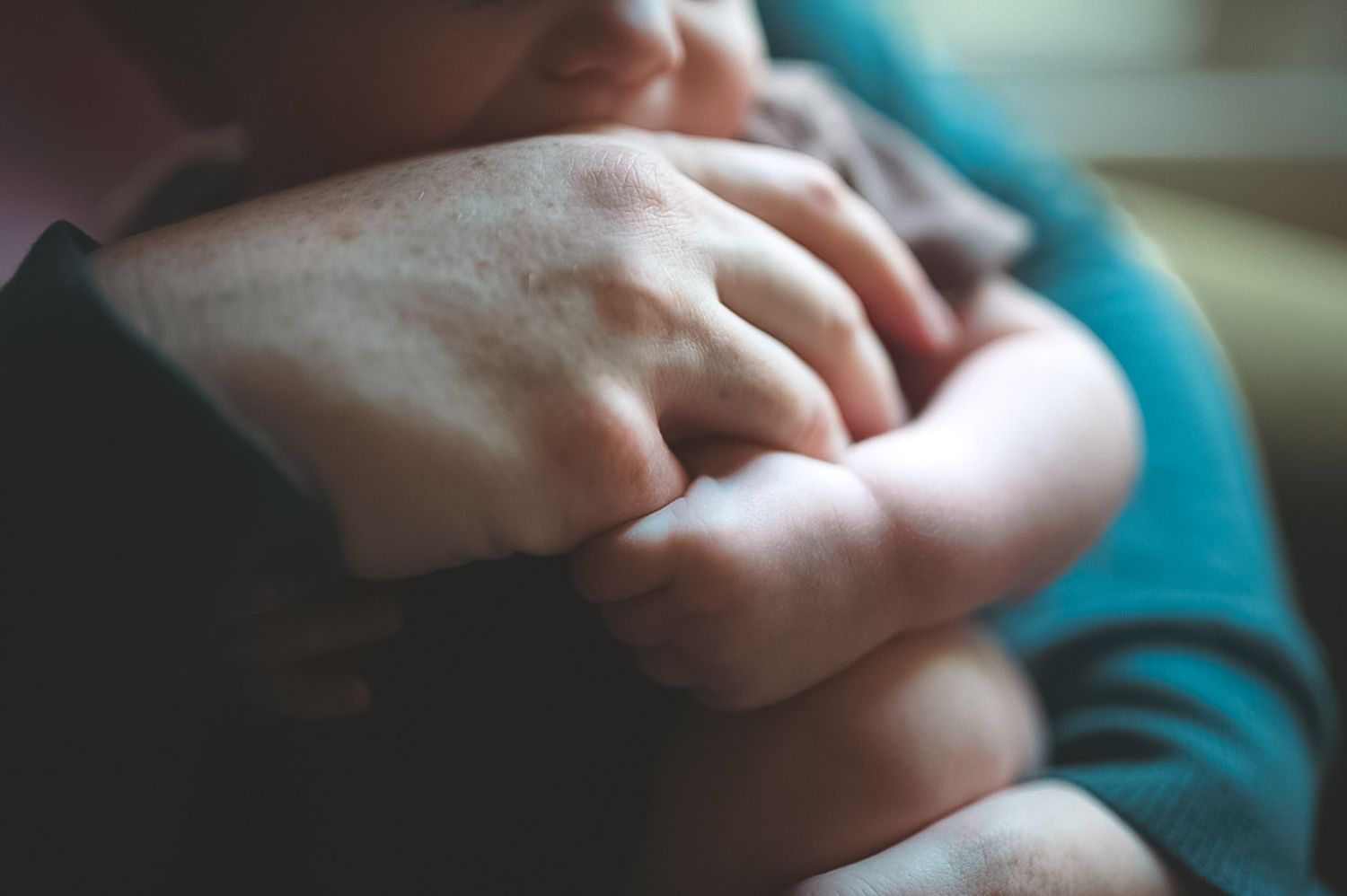 Detail shot of infant holding mom's hand in lifestyle newborn session in Dallas, GA.