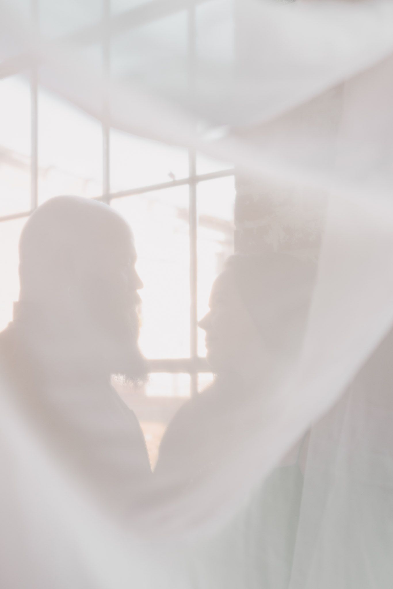 Couple behind curtain at engagement session in northwest Georgia's Lindale Mill.