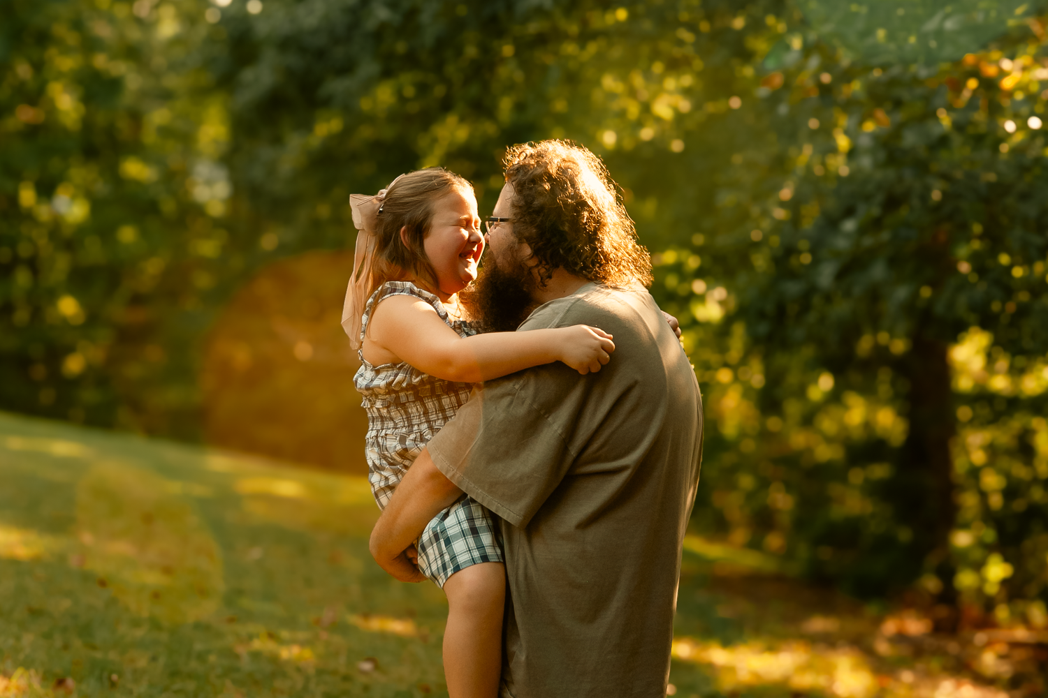Dad and daughter touching noses with golden glow and sun flare for family photos in Cartersville, GA.
