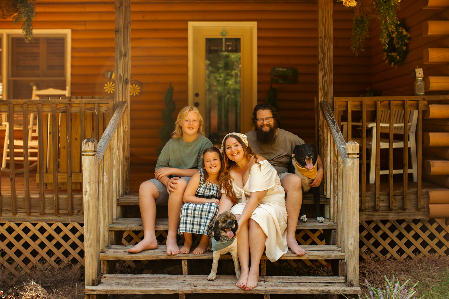 Family sitting on the front porch with their dogs for lifestyle family photos in Cartersville, GA.