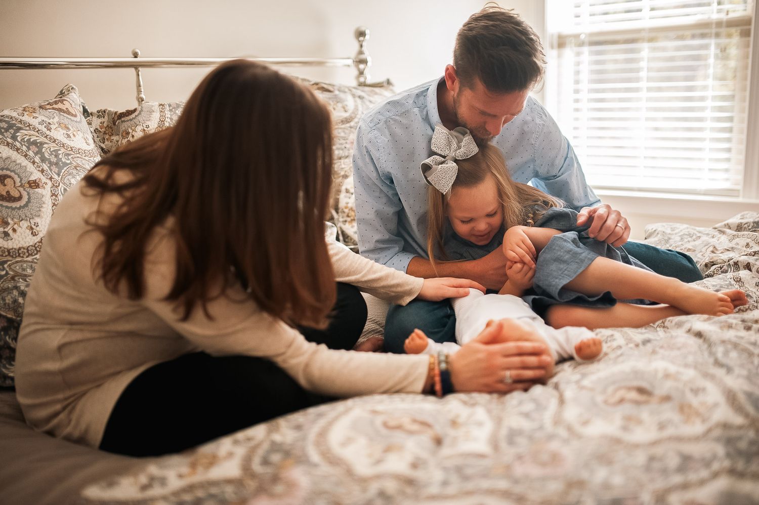 Family playing with baby in mom and dad's bed in Marietta Georgia at home newborn session.