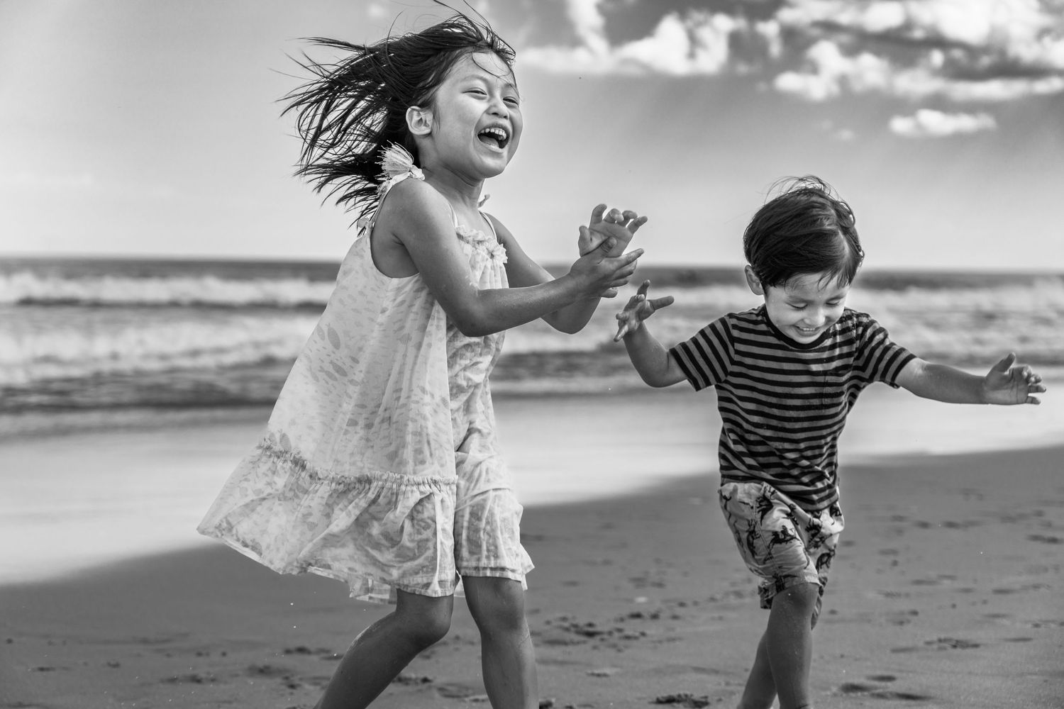 Two children run and play joyfully together on a beach