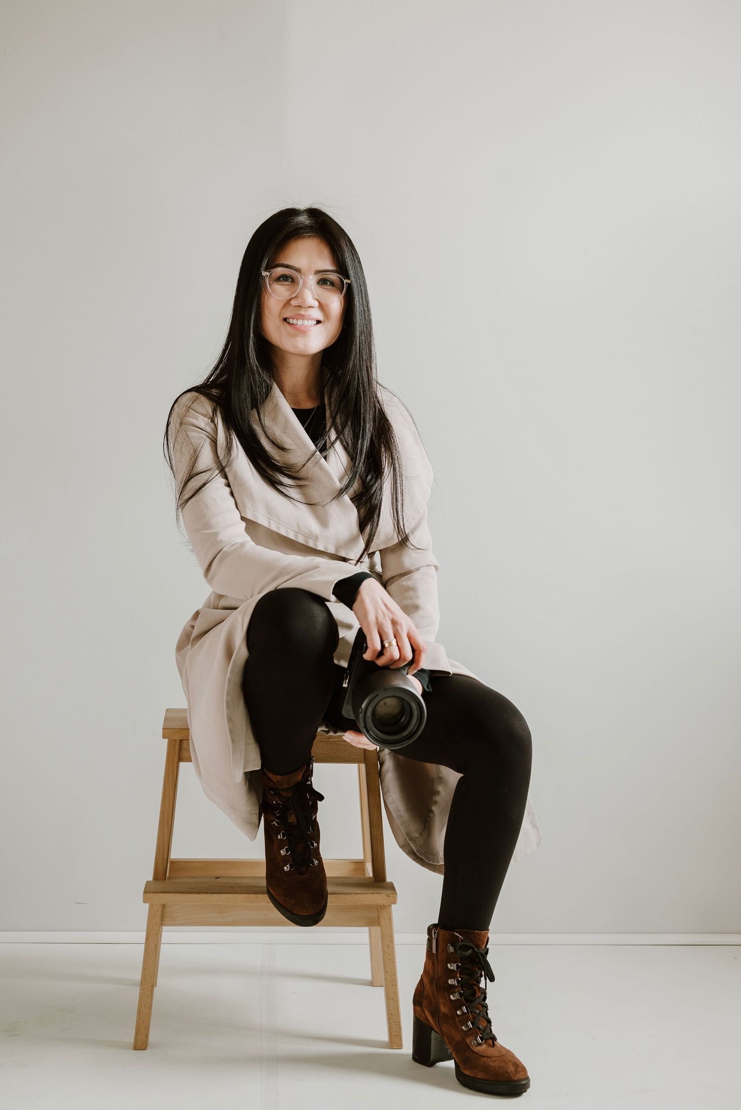 Studio photography session with casual poses on wooden furniture against white backdrop.