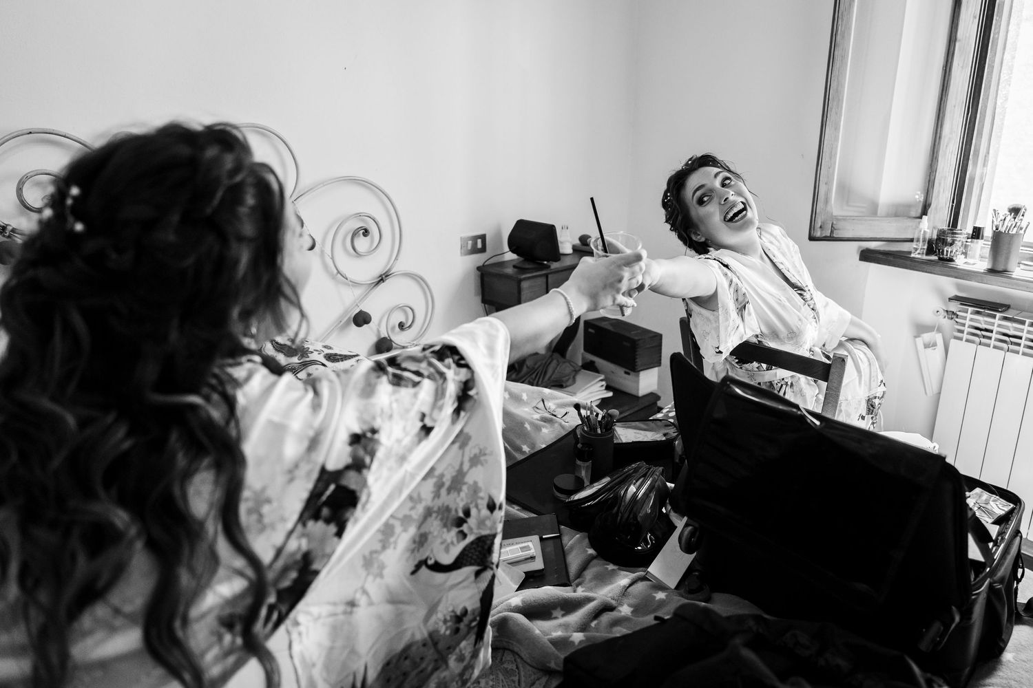 Black and white photo of a laughing groom getting ready on his wedding day.