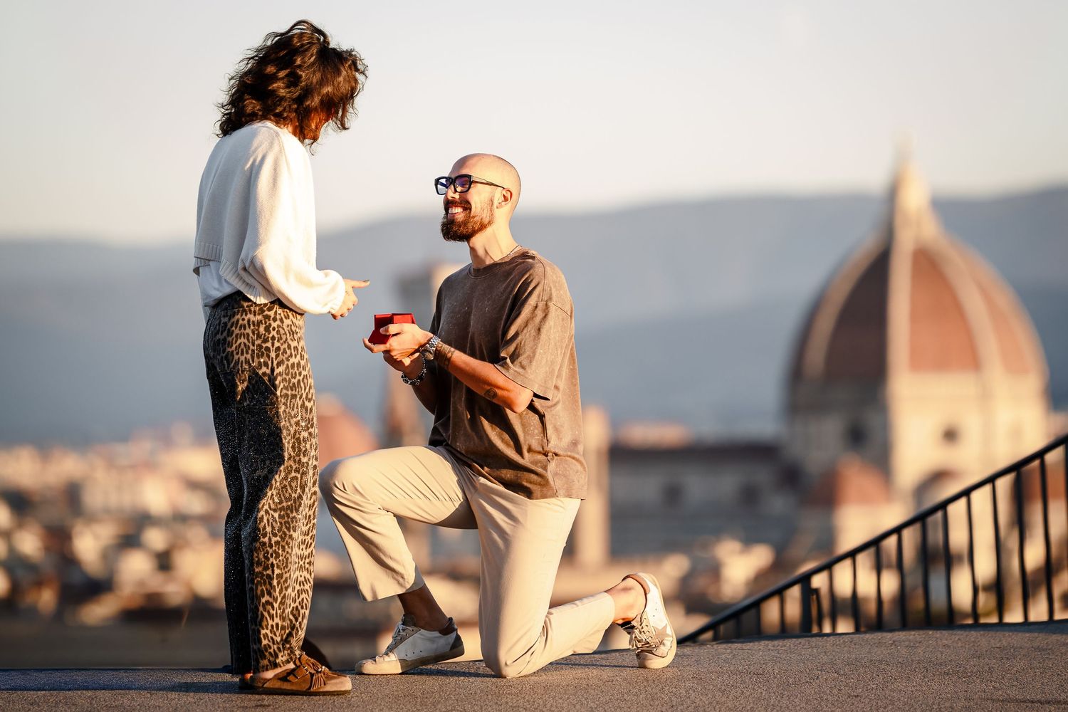 A romantic proposal moment at sunset overlooking Florence with the iconic Duomo cathedral dome in the background.