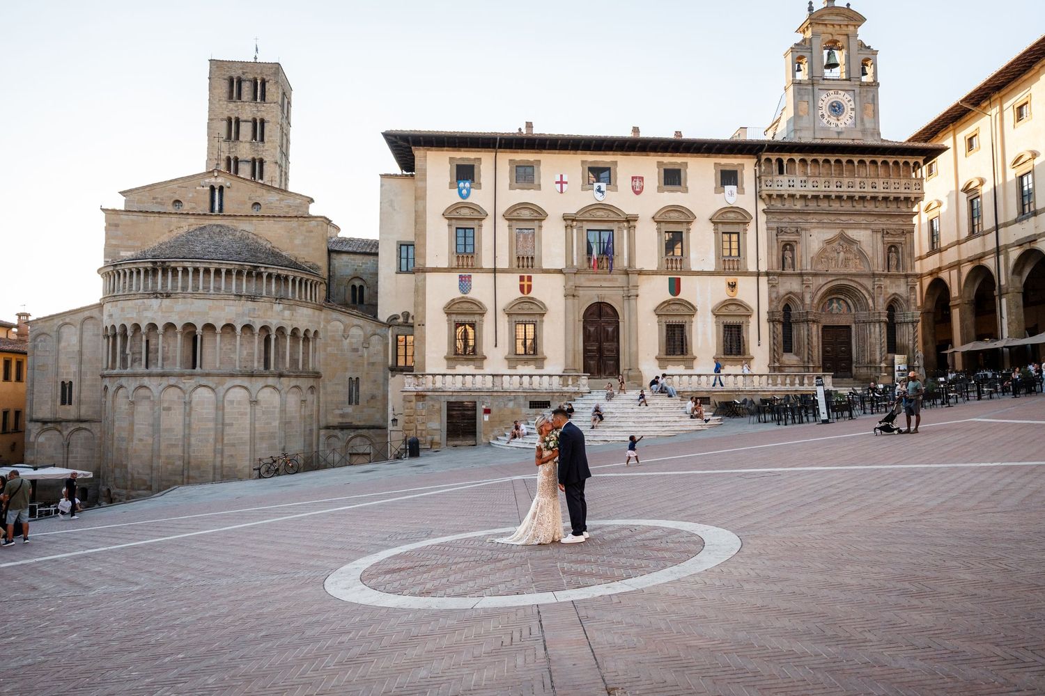 Historic Piazza Grande in Montepulciano, Italy with Renaissance architecture and church facade at sunset.