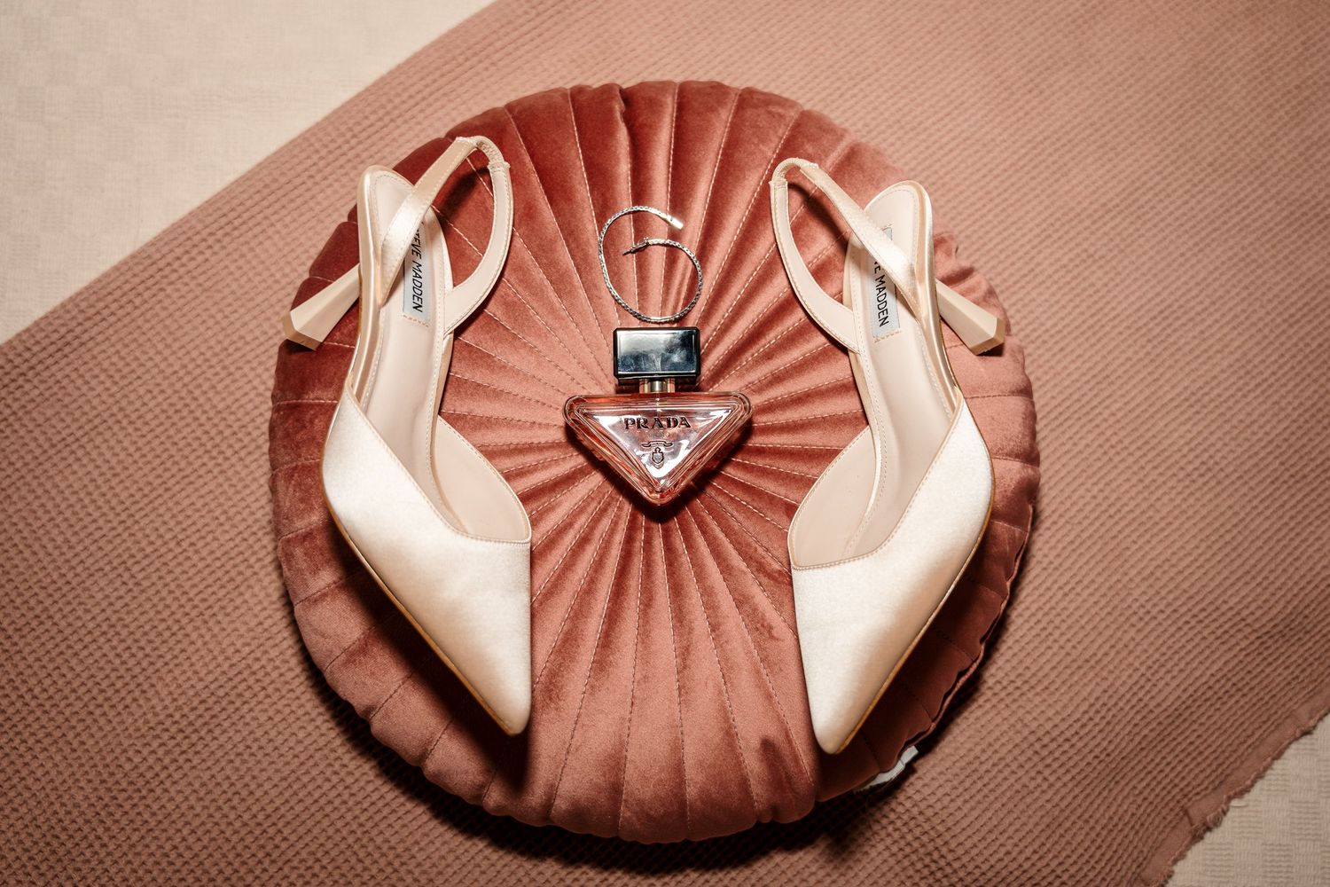 Prada heels and accessories displayed on a pink velvet cushion for a wedding flat lay.
