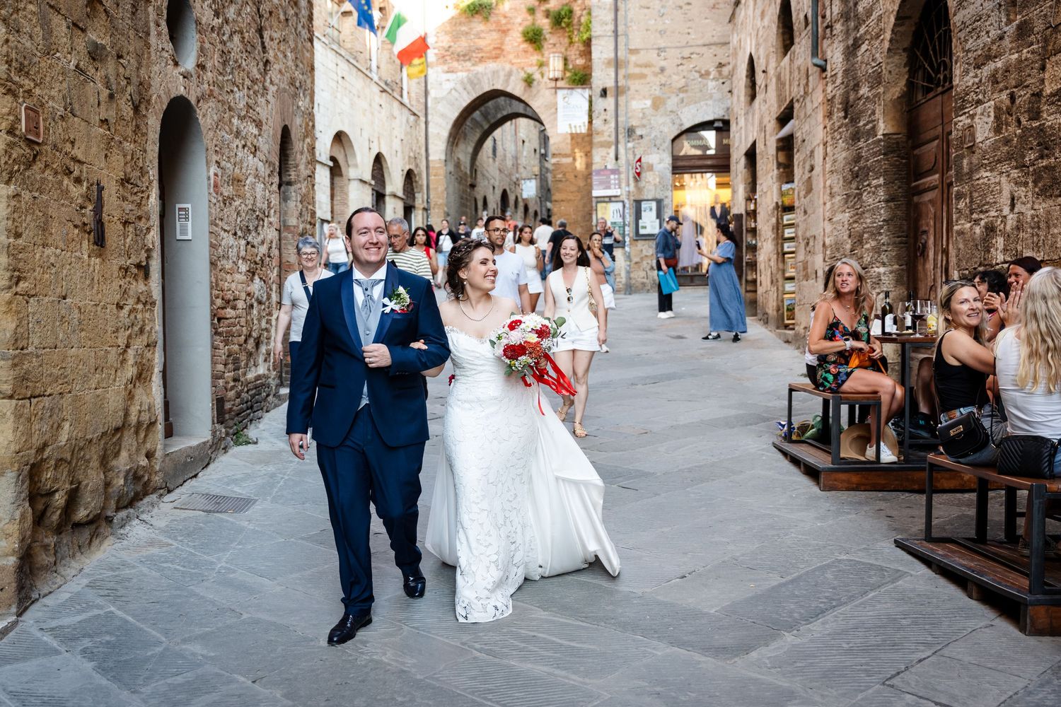 Happy bride and groom walking through a charming Italian stone alleyway after their wedding ceremony.