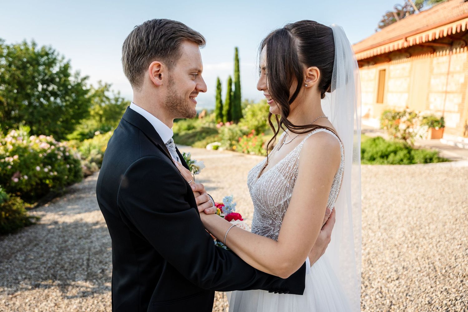 Bride and groom sharing romantic moment outdoors at wedding venue garden.