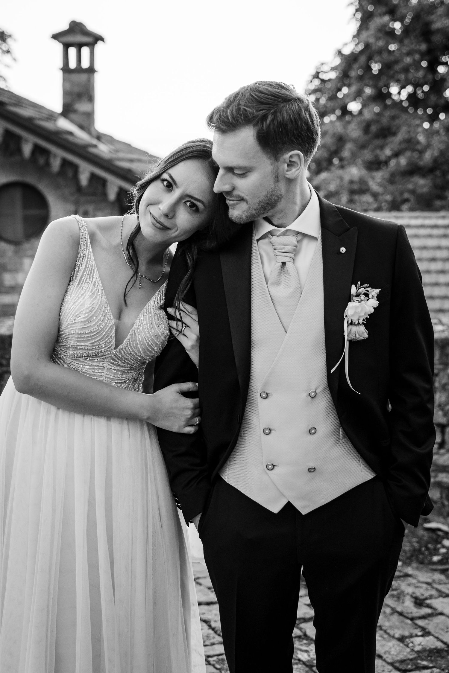 Elegant bride and groom sharing a tender moment in black and white outdoor wedding portrait.