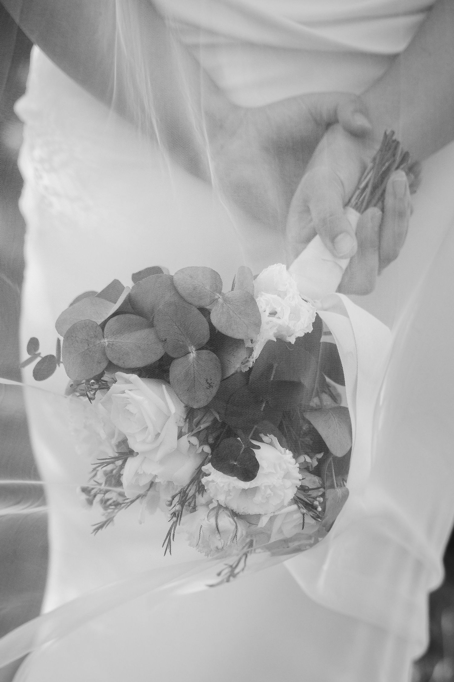 Close-up details of an elegant white wedding bouquet with mixed flowers and greenery.