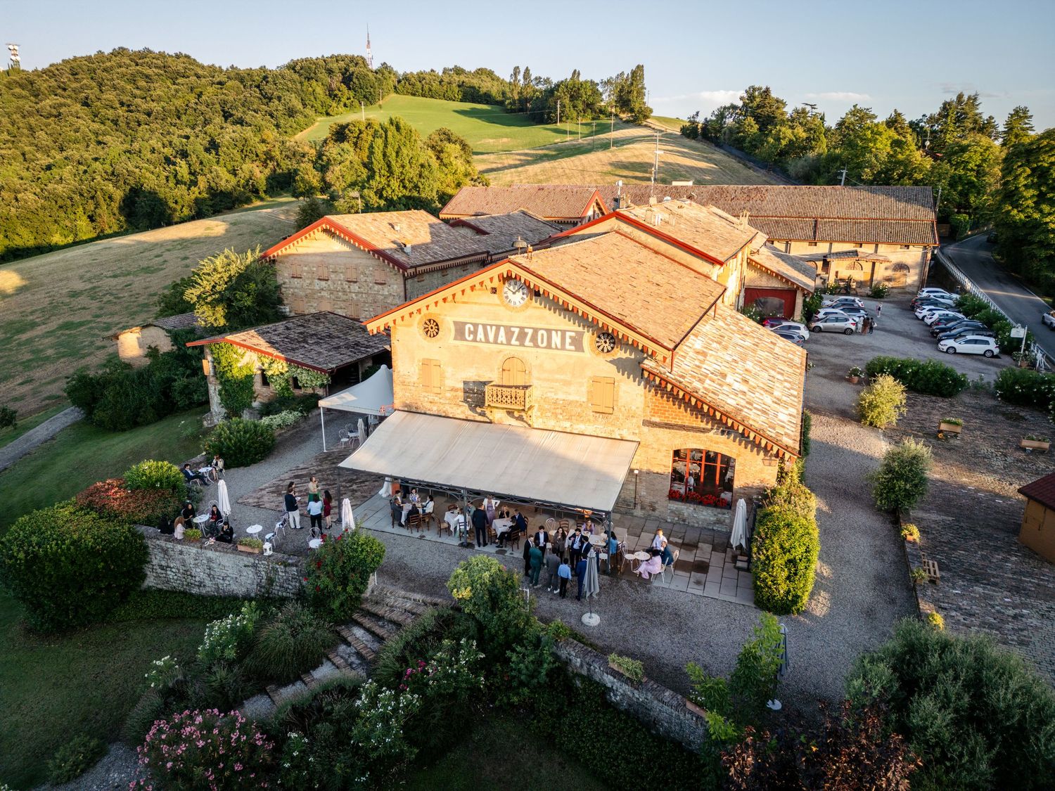 Aerial view of Meinbelle rustic stone venue surrounded by lush green hills with guests gathered outside.