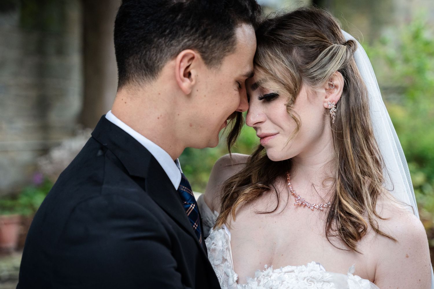 Romantic wedding couple embraces in an intimate outdoor portrait series against a natural garden backdrop.