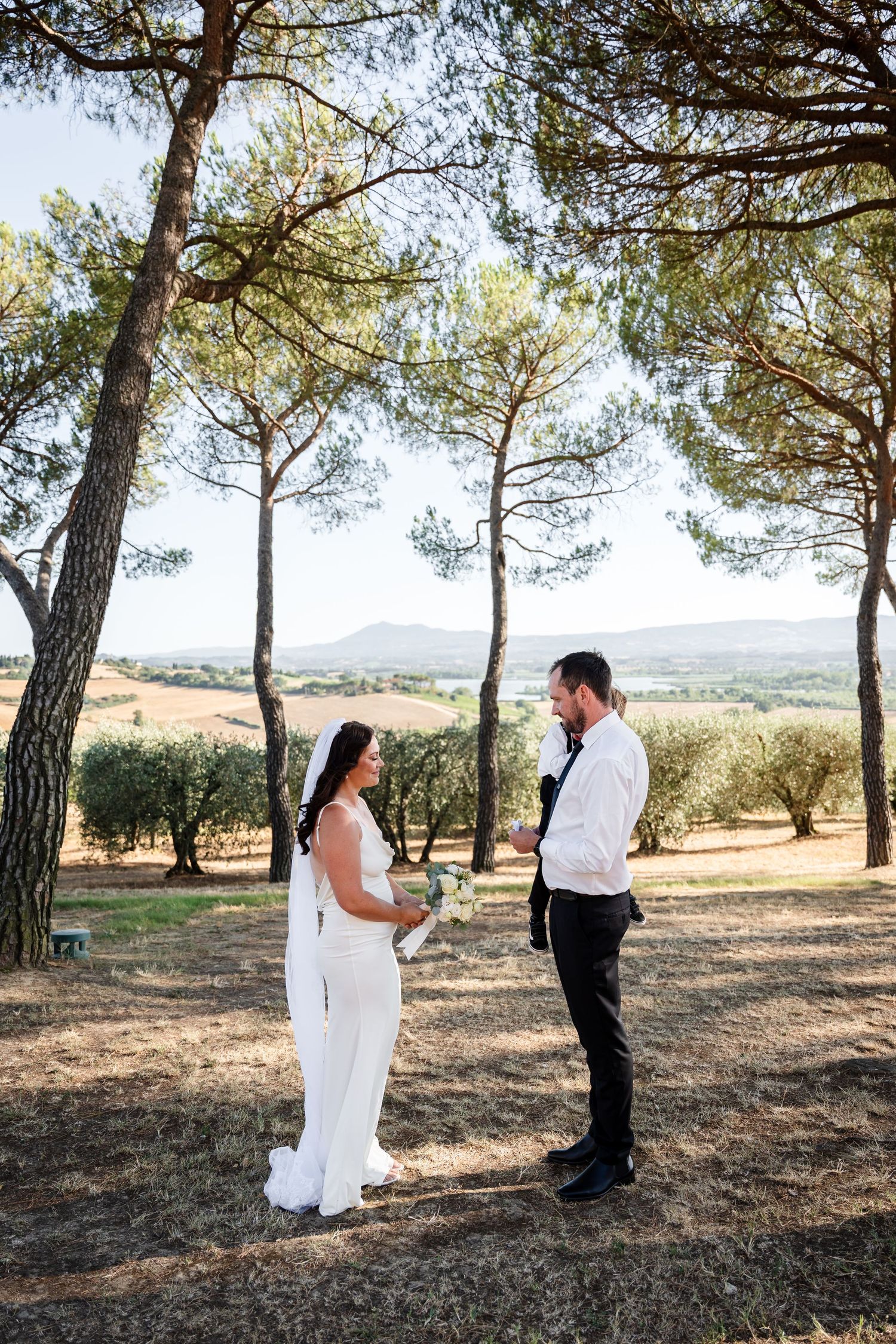 A romantic wedding photo sequence showing a couple in white attire posing under tall pine trees in a rustic outdoor setting.