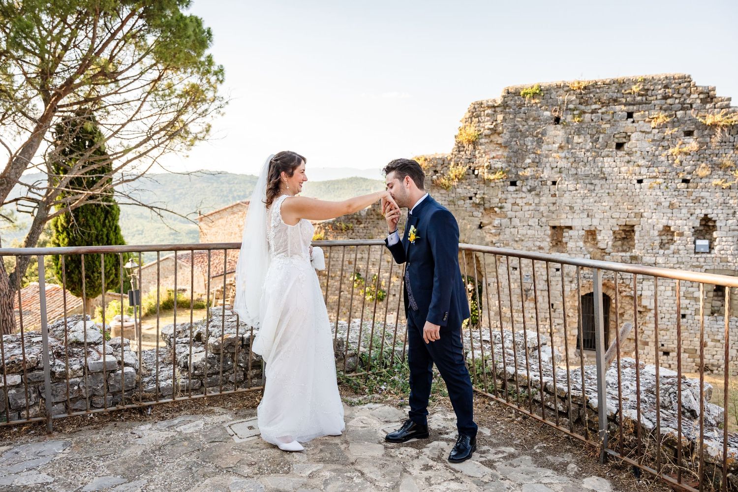 Bride and groom share a romantic moment on a stone terrace with ancient ruins backdrop during their outdoor wedding ceremony.