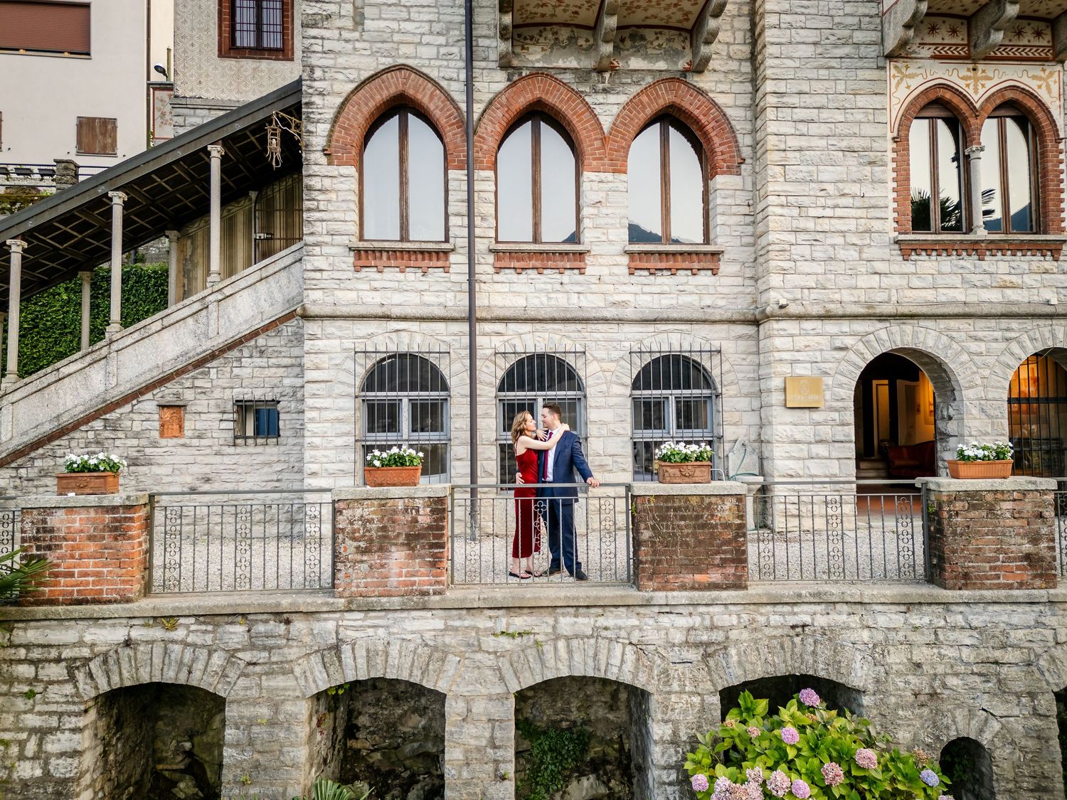 Historic stone building with arched windows and ornate architectural details along a hillside street in Europe.