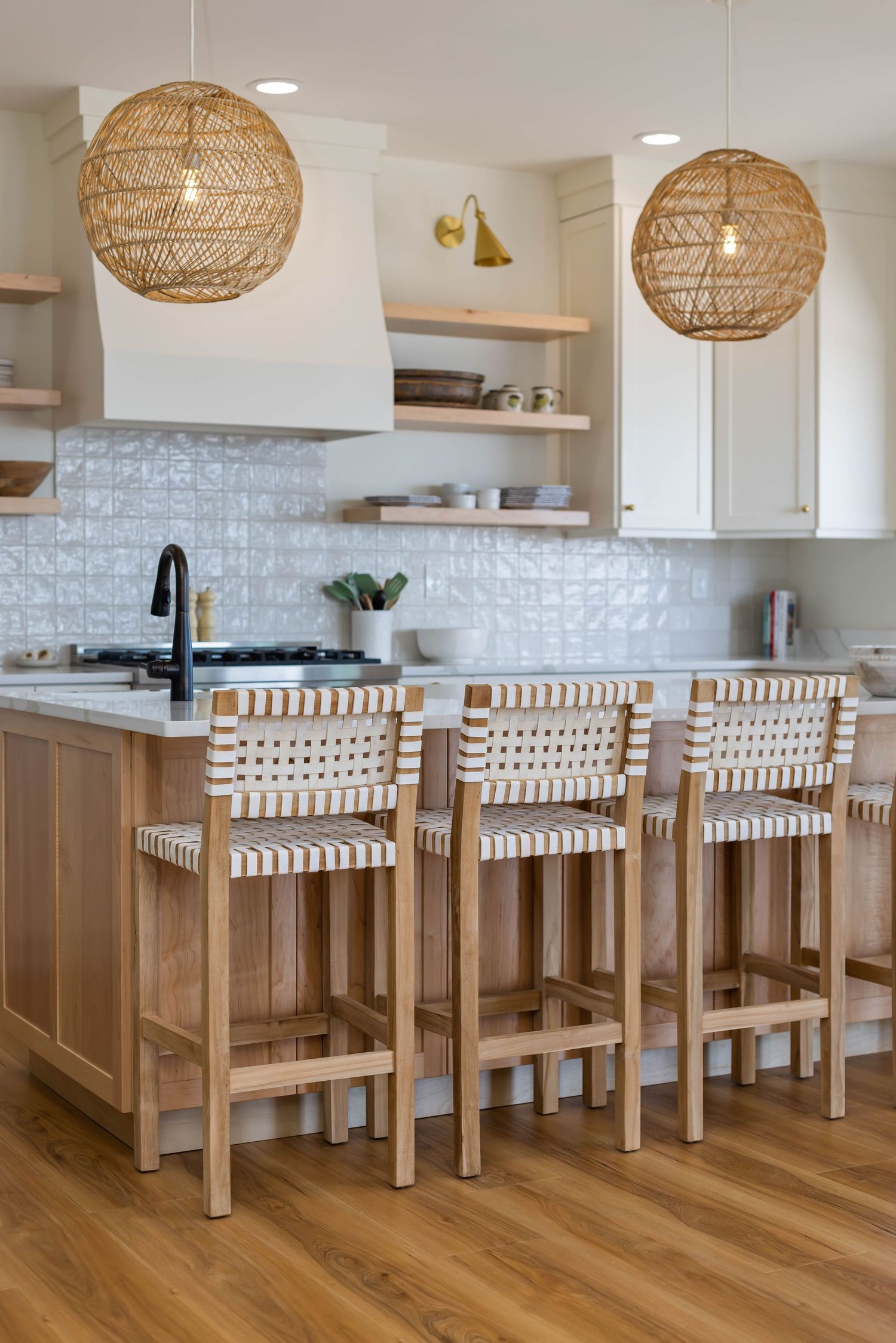 Bright kitchen with wood bar stools, woven pendant lights, and white tile backsplash.