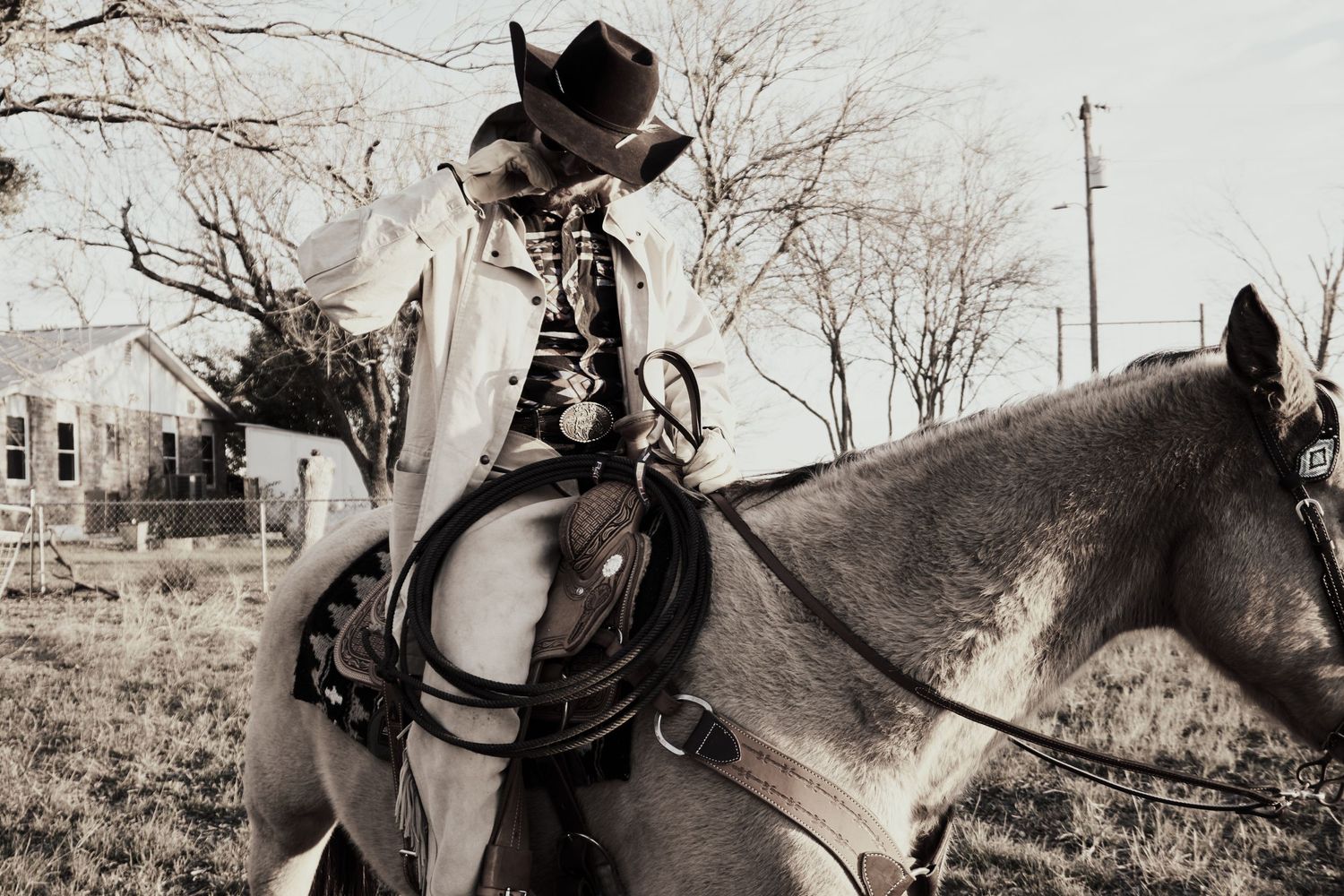 A black and white photo of a rider on horseback wearing classic western attire.