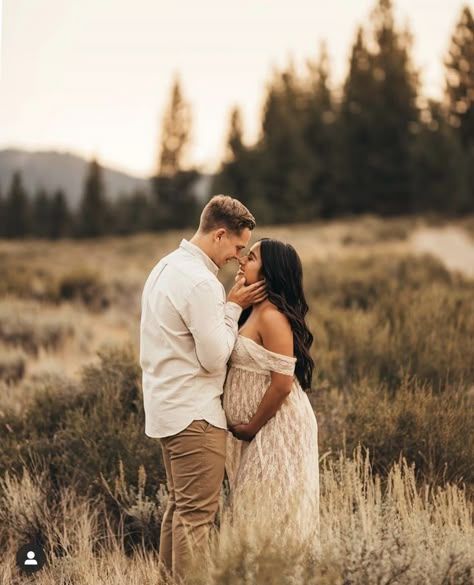 A romantic sunset maternity photo shoot in a golden mountain meadow with tall evergreens in the background.