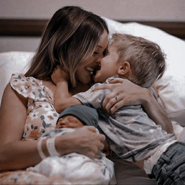 A tender family moment captured as parent and child share laughter while cuddling on soft bedding.