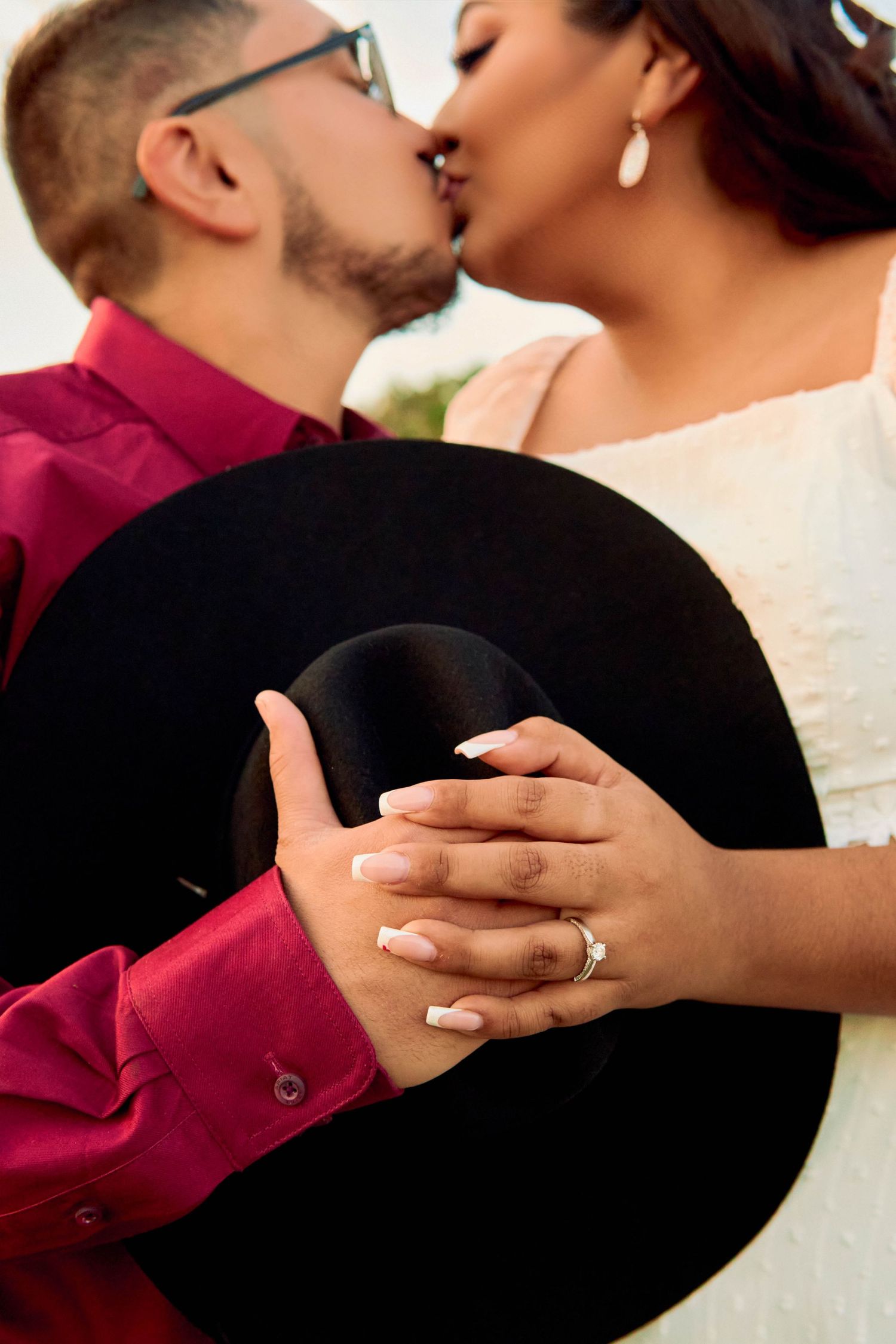 A romantic moment between newlyweds holding a black cowboy hat showing off a wedding ring.