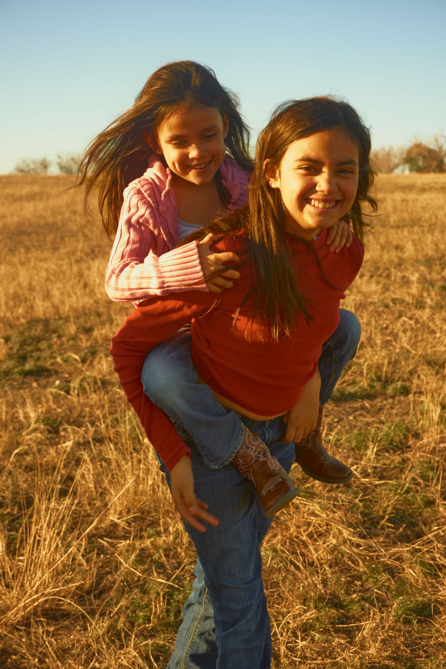 Two people having fun with a piggyback ride in a sunny autumn field.