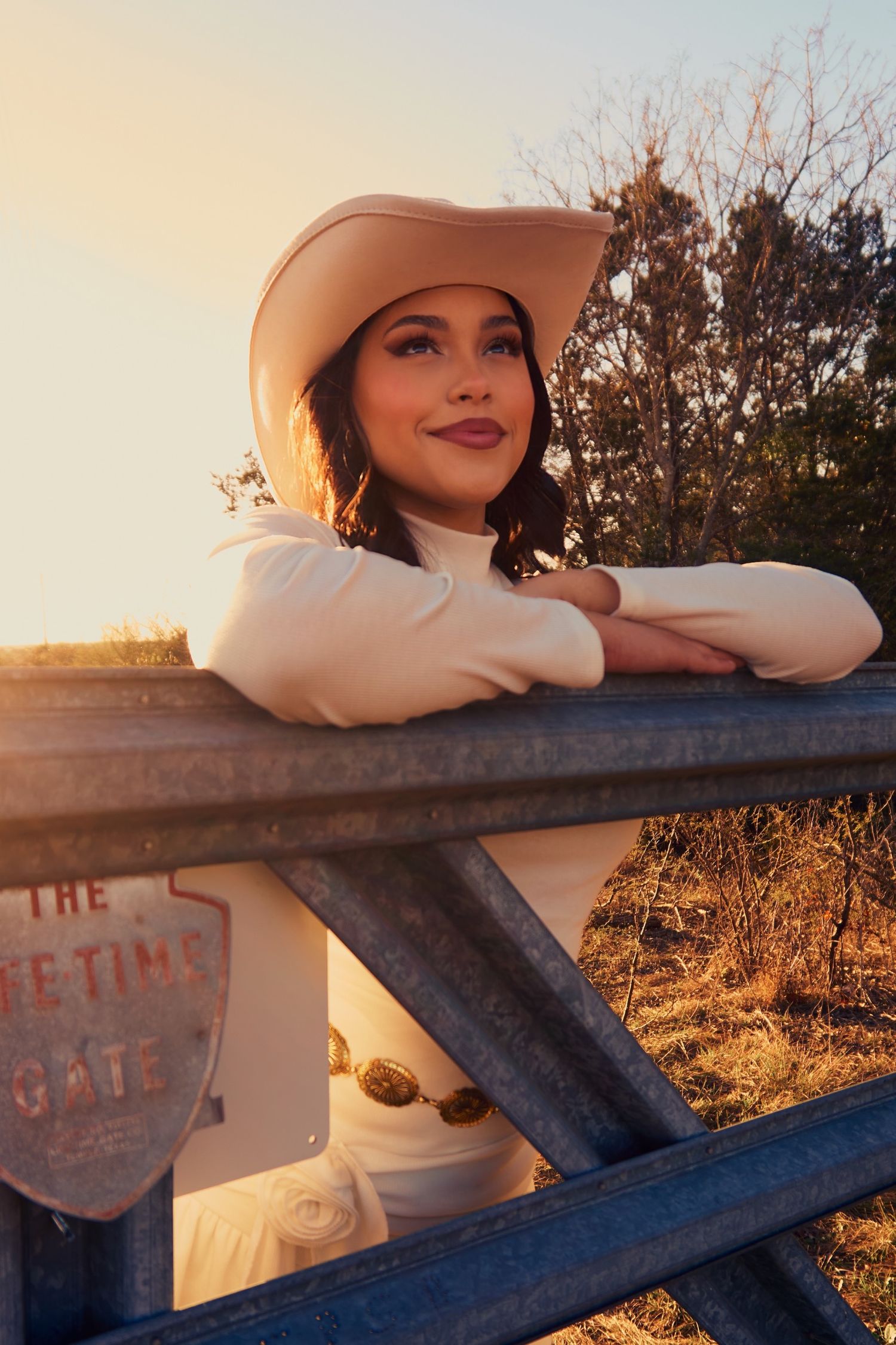 Golden hour country portrait at rustic metal gate.