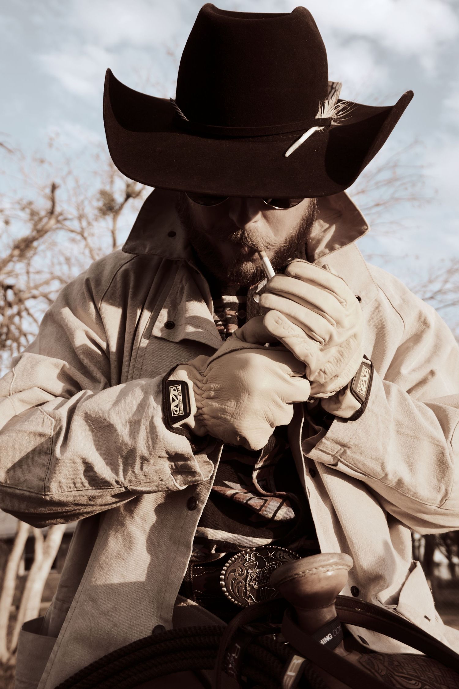 A silhouetted figure in a cowboy hat lighting up against a bright sky backdrop.