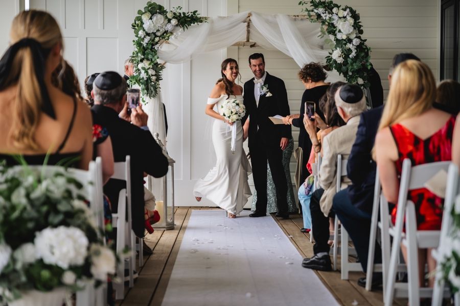 Wedding party members gather in a bright indoor venue during a formal celebration.