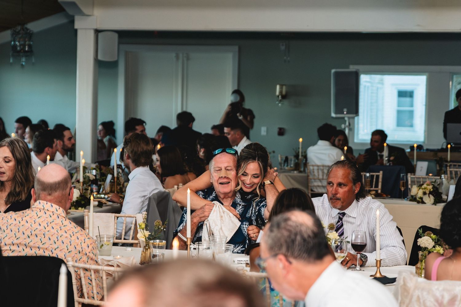 Wedding reception guests seated at round tables in a banquet hall enjoying dinner and conversation.