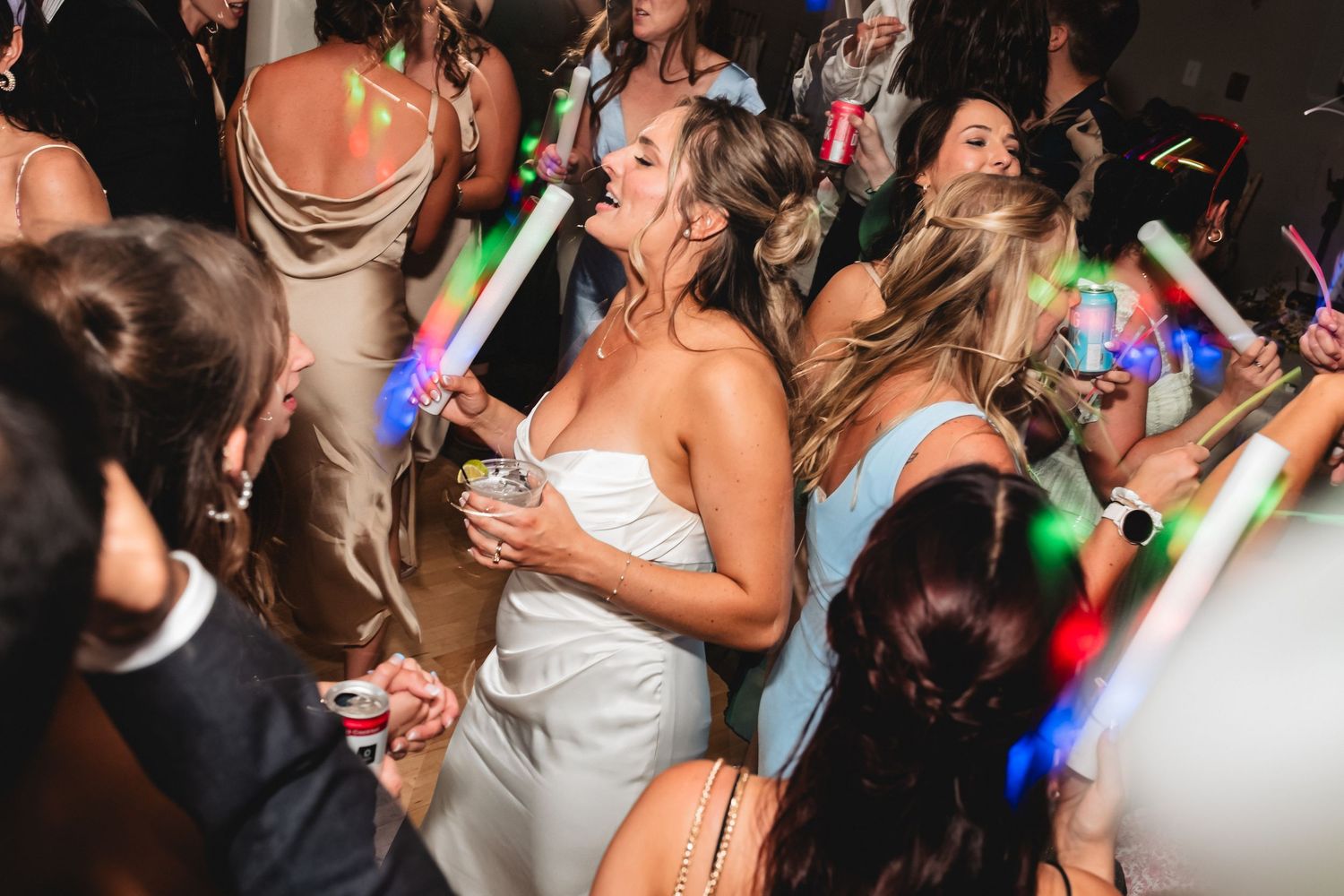 People dancing and celebrating at a lively party with colorful lights illuminating the dance floor.