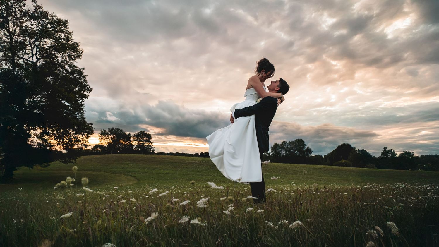 Panoramic wedding photo series showing couple in romantic poses against dramatic sunset sky in rural countryside setting.
