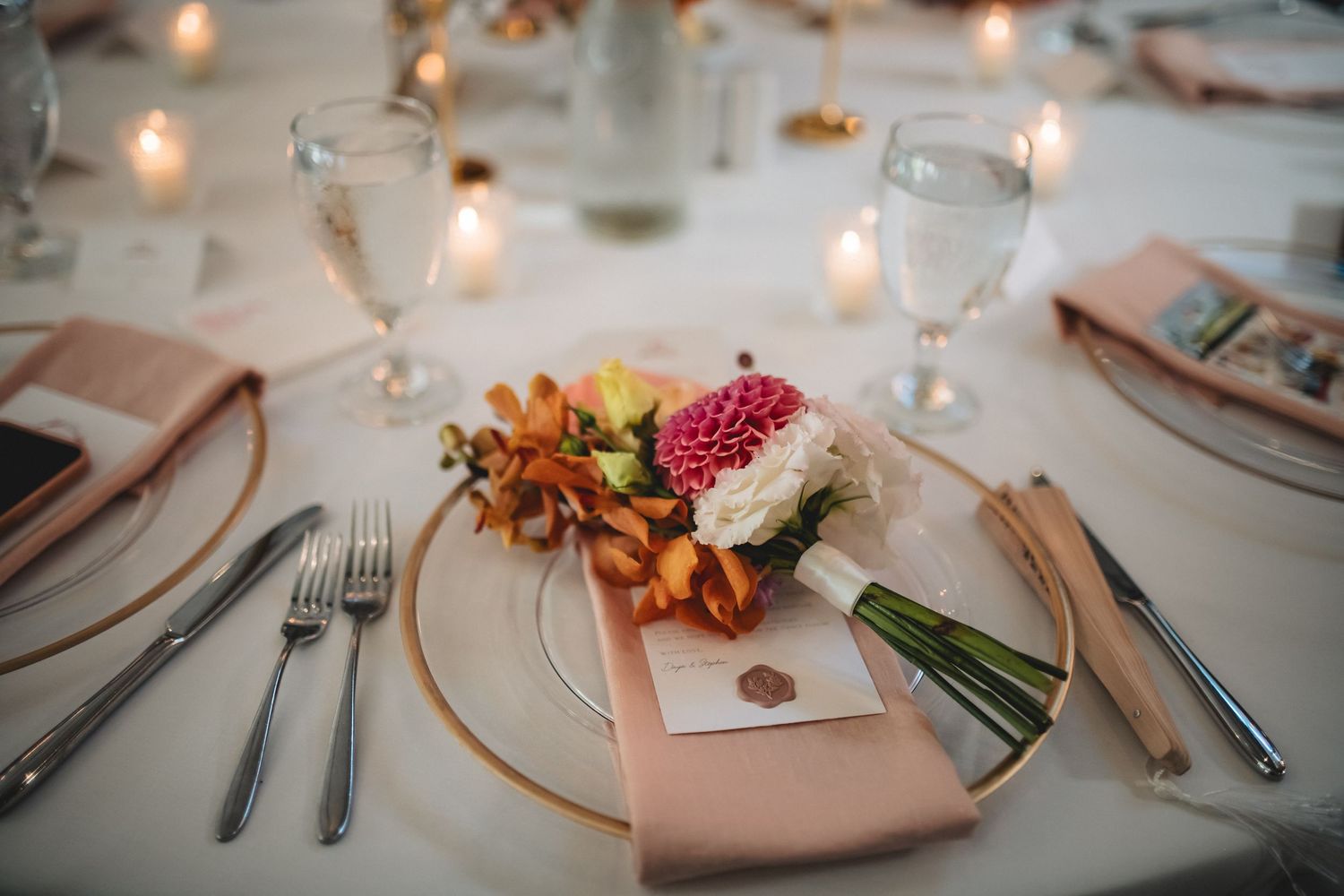 Elegant table settings with soft candlelight, white plates, and autumn-inspired decor create a romantic dining atmosphere.