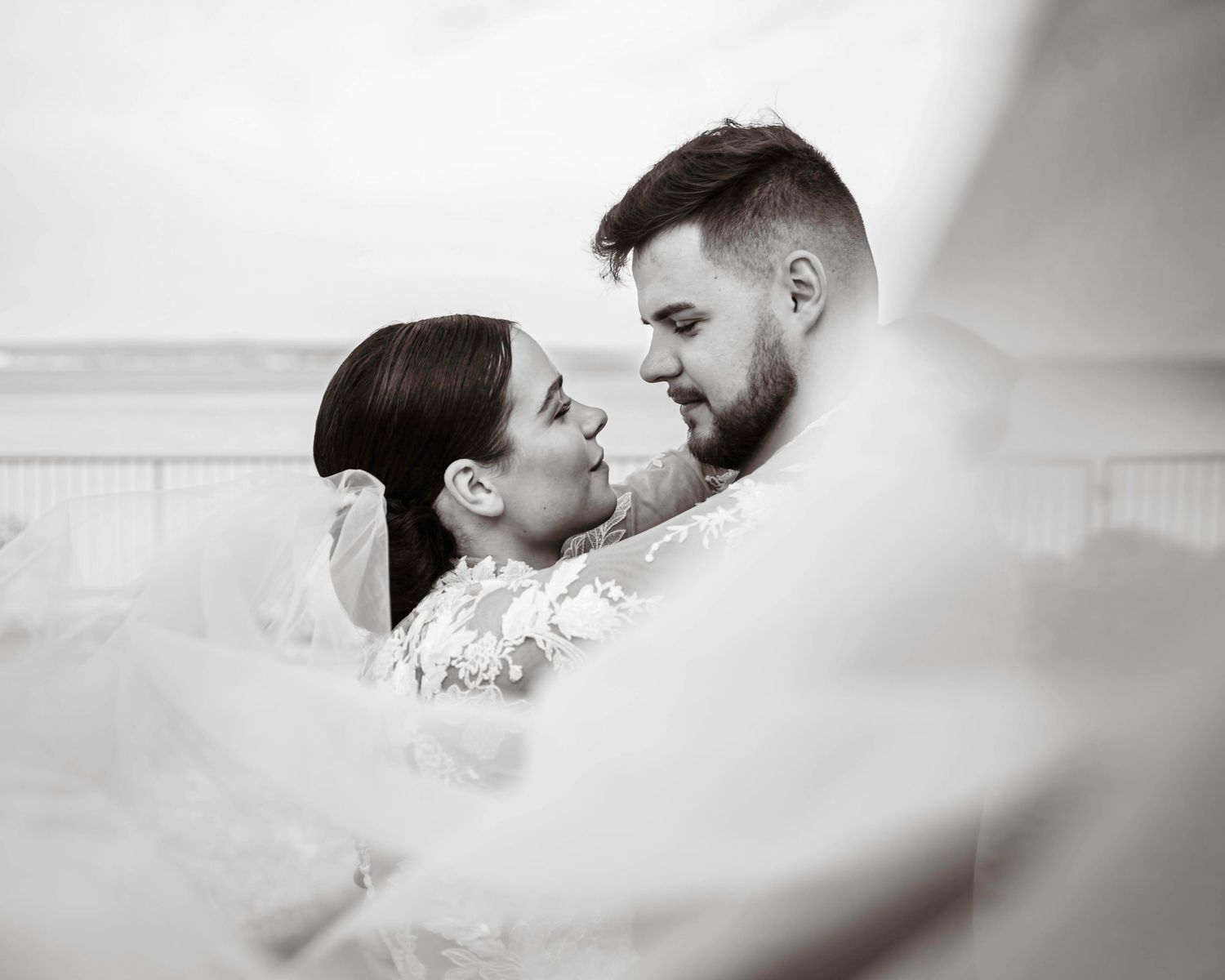 Black and white romantic portrait of a couple sharing a tender moment outdoors with soft dreamy lighting.