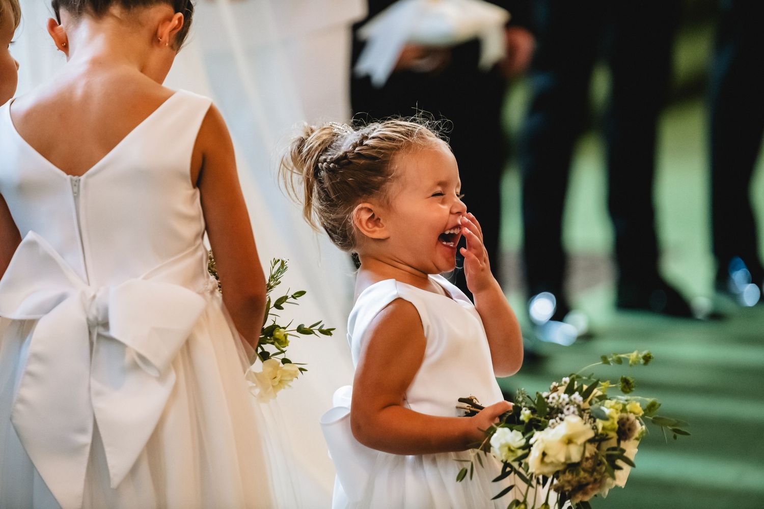 A joyful wedding celebration with a couple dancing and embracing while holding white floral bouquets in an outdoor setting.